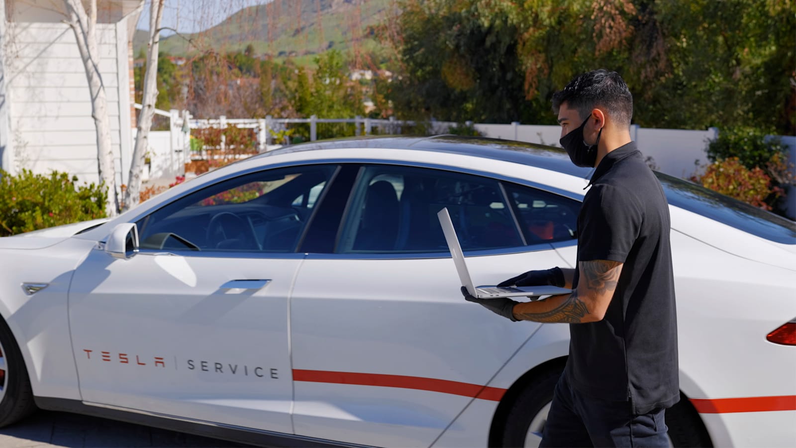 Technik serwisu Tesli przy aucie z laptopem diagnostycznym